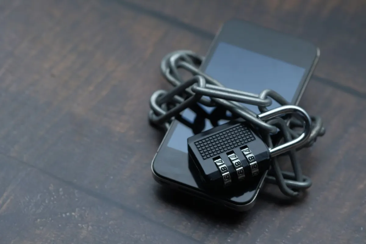 Smartphone wrapped in chain and padlock symbolising online scam safety in Johor Bahru