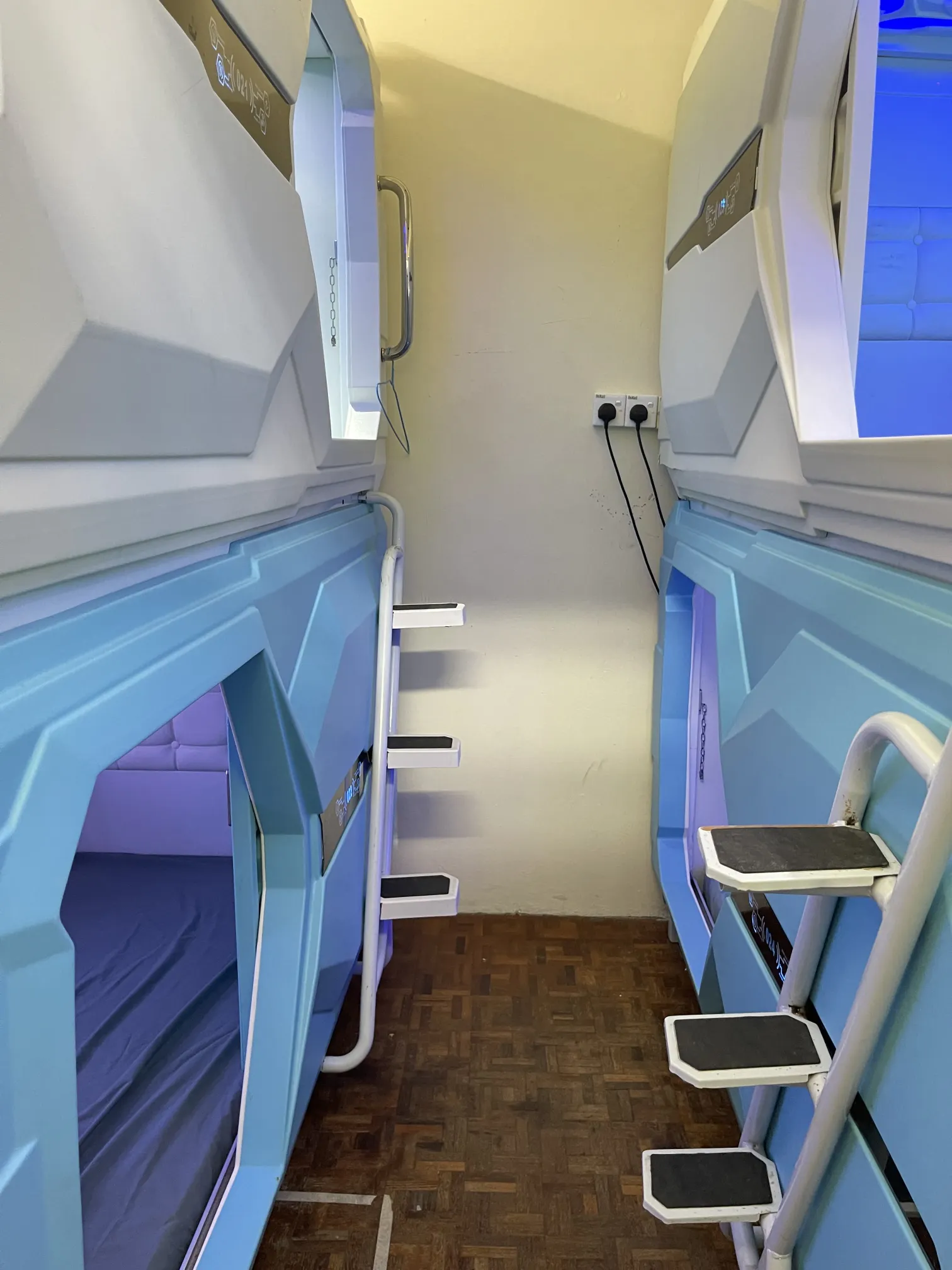 Row of Japanese-style capsule pods with individual privacy doors at Pelangi Capsule Hostel