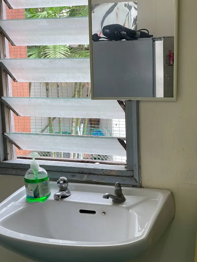 Shared washbasin area with mirror and amenities at Pelangi Capsule Hostel